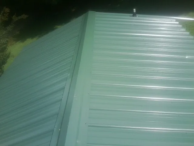 New green metal panels meeting at the ridge of a roof — Flat Roof Repair work by our crew in Preston